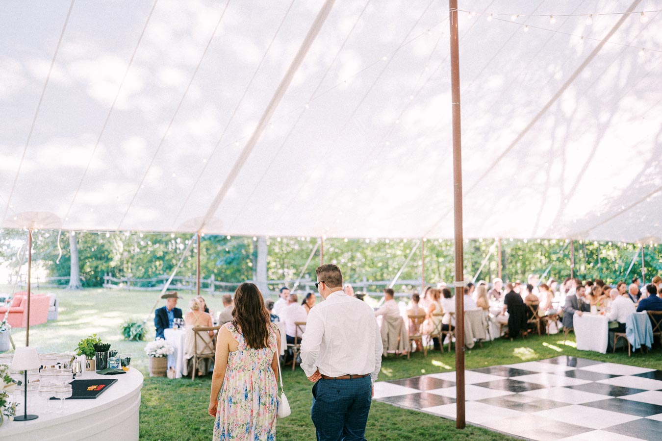 Outdoor tented wedding reception on a private farm estate near Chatham-Kent, Ontario, with guests, tables, flowers, and a checkered dance floor.