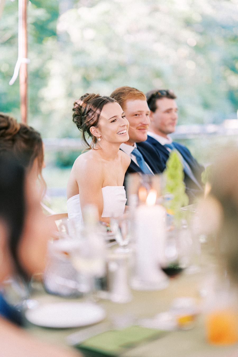 Bride and guests smiling during a tented outdoor wedding dinner on a private farm estate near Chatham-Kent, Ontario, Canada.