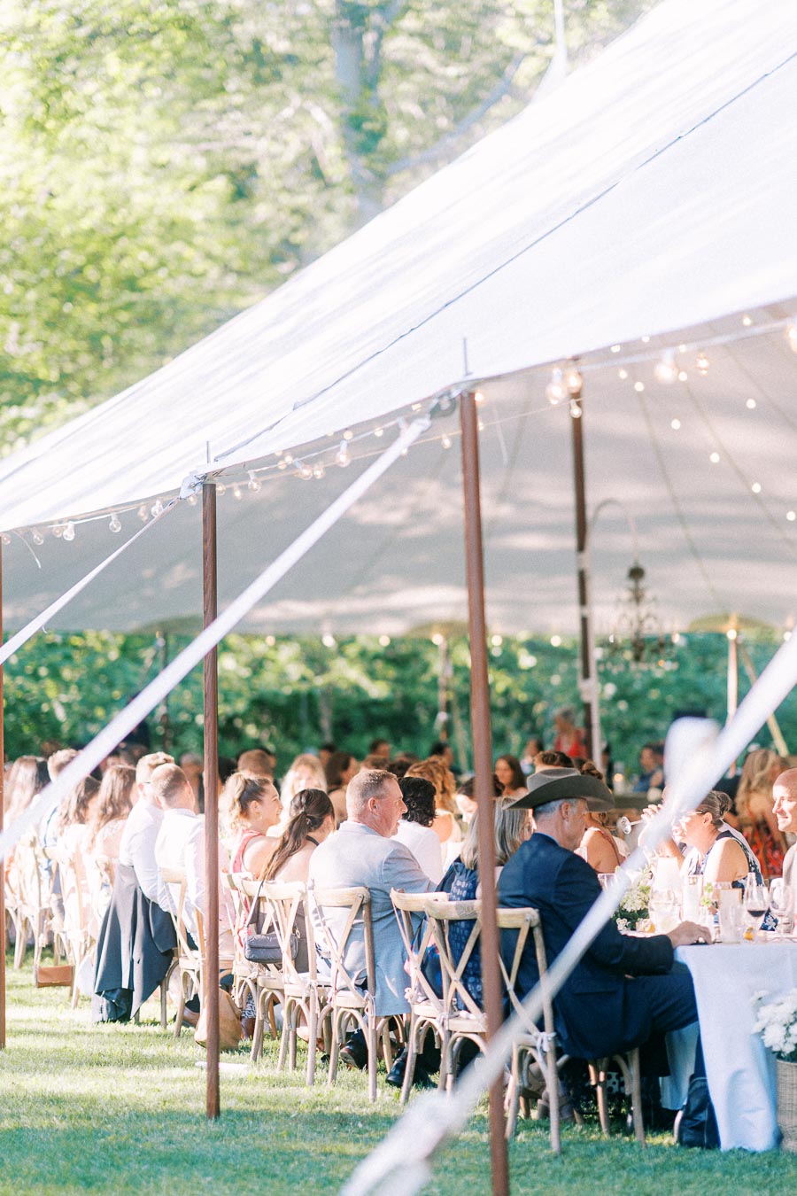 Guests seated at long tables under a white wedding tent on a private farm estate near Chatham-Kent, Ontario, Canada.