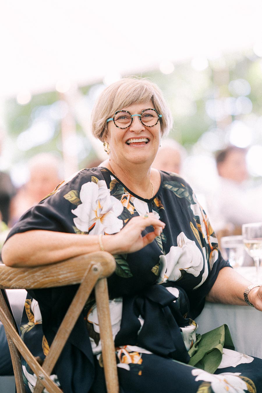 Smiling female wedding guest in glasses seated at an outdoor tented farm wedding reception near Chatham-Kent, Ontario, Canada.