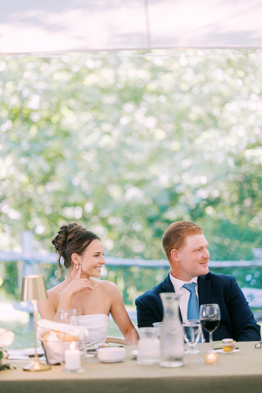 Bride and groom seated at a decorated outdoor wedding reception table under a tent on a private estate near Chatham-Kent, Ontario.