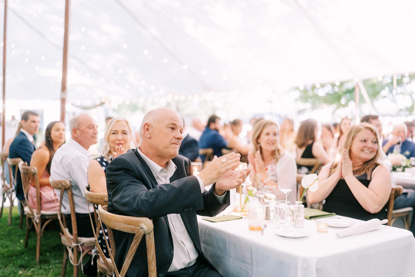 Wedding guests applauding during a tented outdoor reception on a private farm estate near Chatham-Kent, Ontario, Canada.