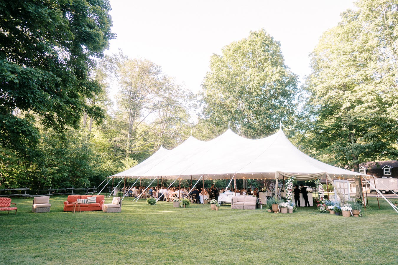 White wedding tent on a grassy private estate near Chatham-Kent, Ontario, with guests dining outdoors under trees.