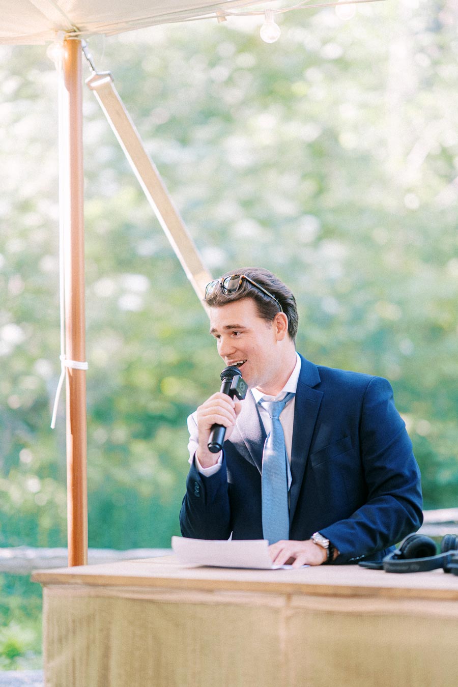 Man in blue suit giving a wedding speech with a microphone under an outdoor tent near Chatham-Kent, Ontario, Canada.