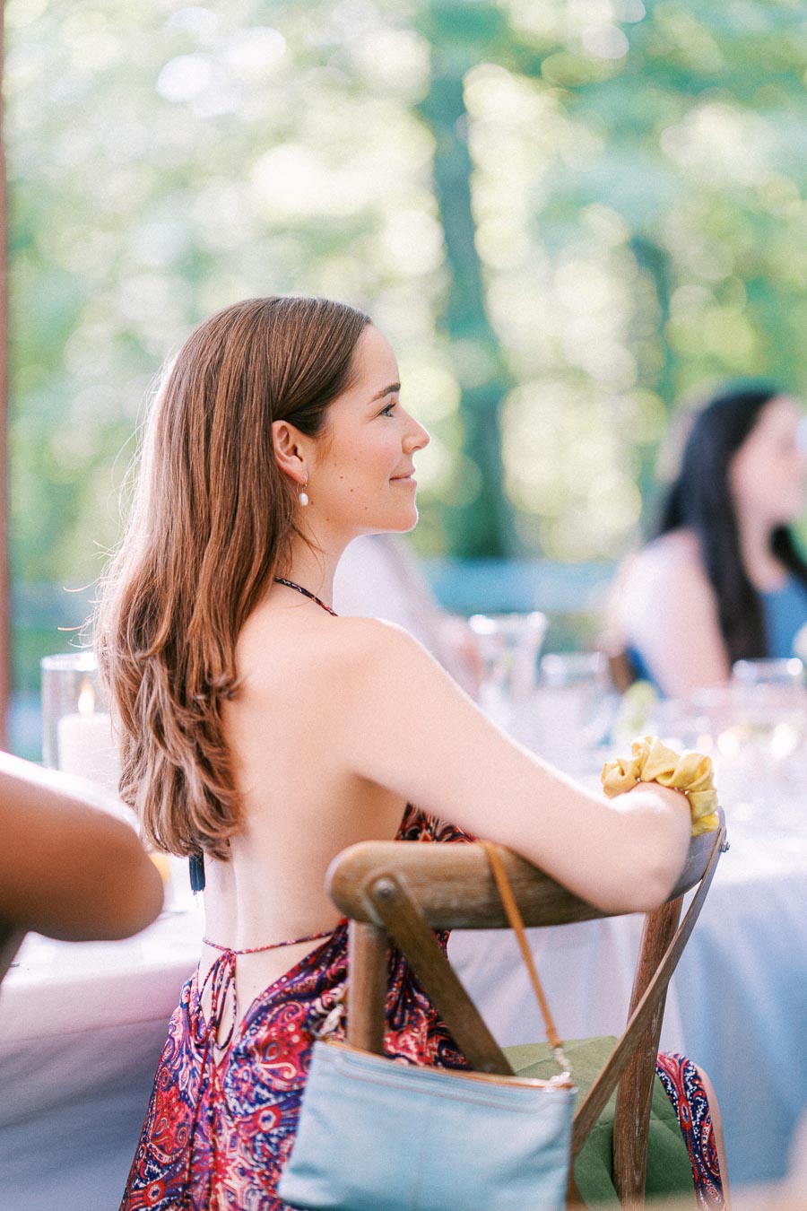Woman seated at an outdoor wedding reception table on a private estate near Chatham-Kent, Ontario, with candles, glassware, and wooded background.