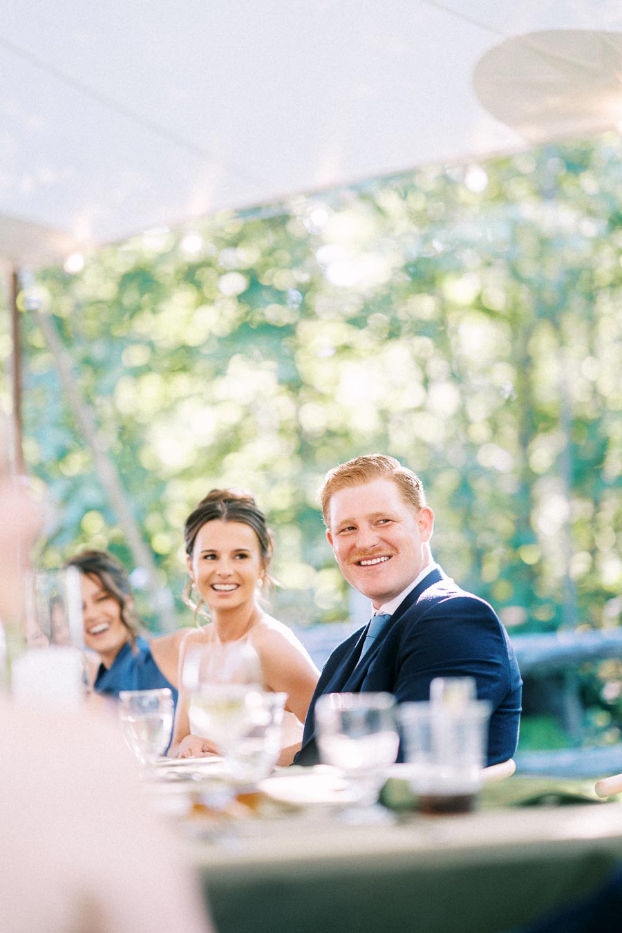 Bride and groom smiling at an outdoor tented wedding reception on a private estate near Chatham-Kent, Ontario, Canada.