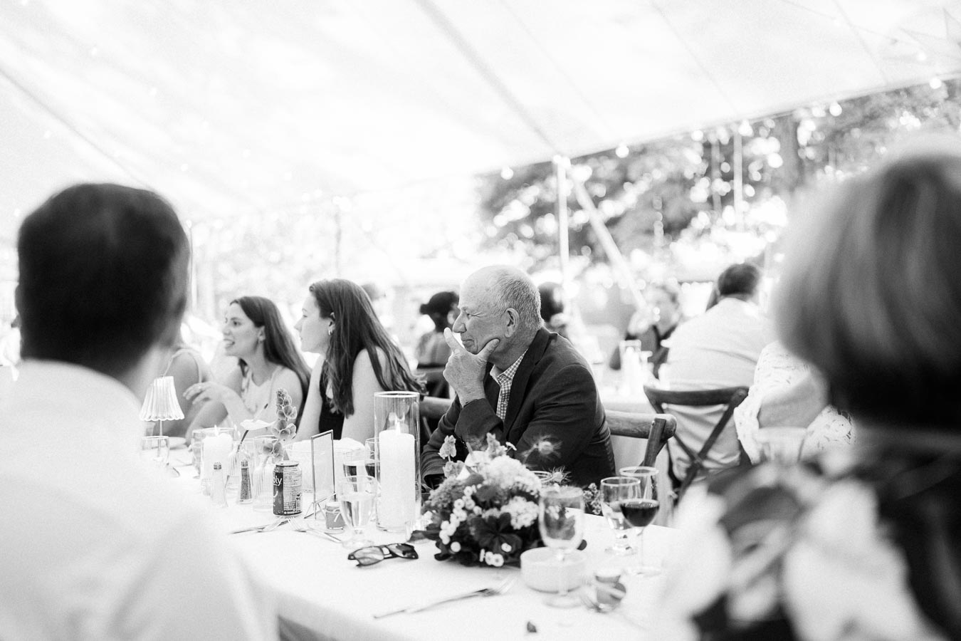 Black and white photo of wedding guests seated at a tented outdoor reception dinner on a private farm estate near Chatham-Kent, Ontario.