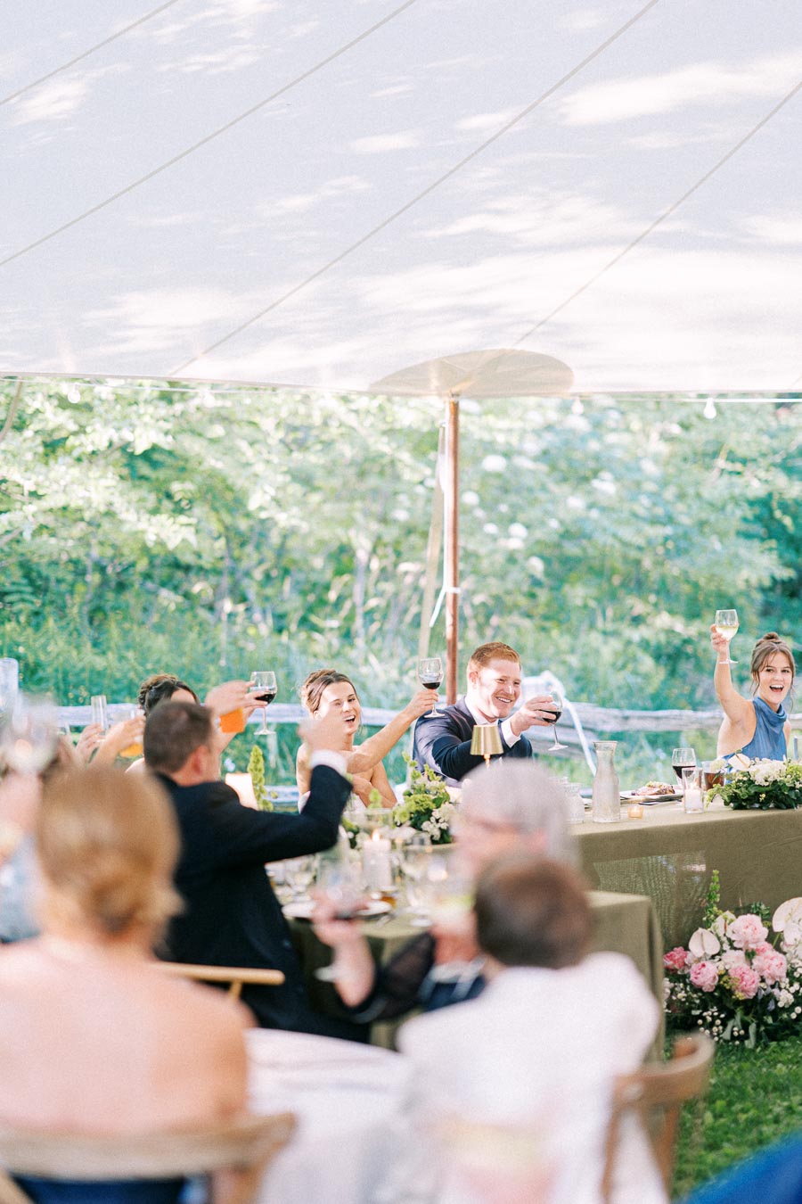 Wedding guests raise glasses during an outdoor tented reception on a private estate near Chatham-Kent, Ontario, Canada.