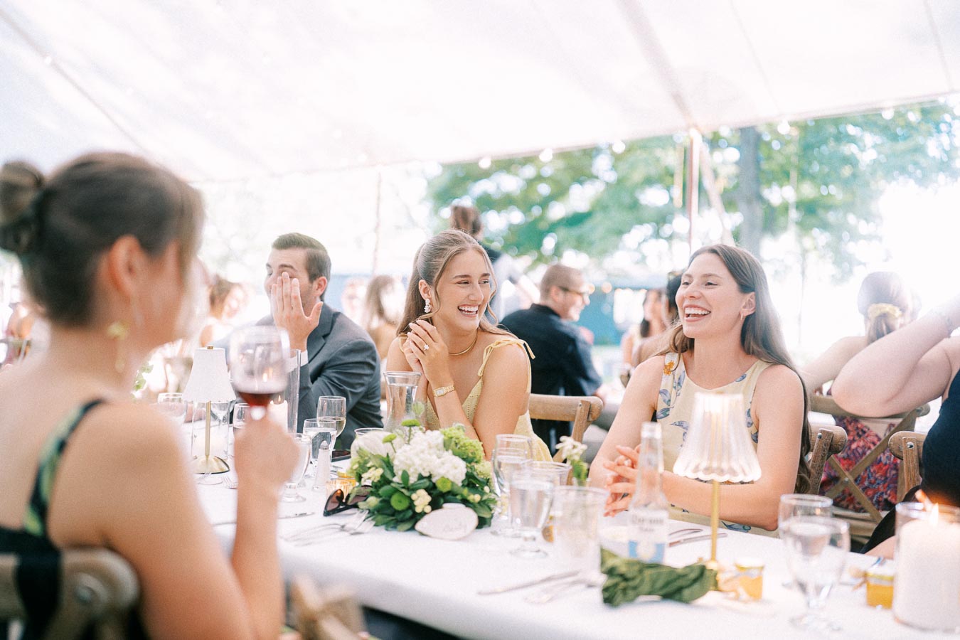 Wedding guests laughing at a tented outdoor reception dinner on a private farm estate near Chatham-Kent, Ontario, Canada.