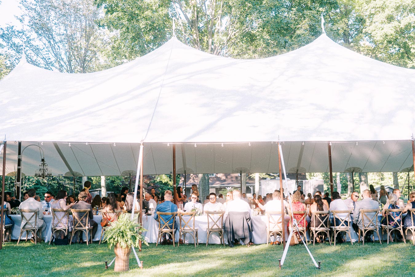 Outdoor wedding reception dinner under a large white tent on a private farm estate near Chatham-Kent, Ontario, Canada.
