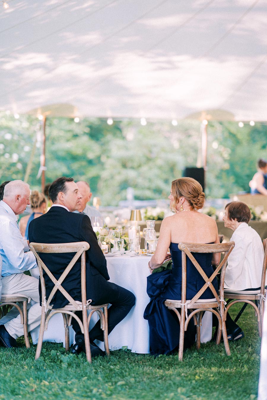 Wedding guests seated at a round dinner table under a white tent on a private farm estate near Chatham-Kent, Ontario, Canada.