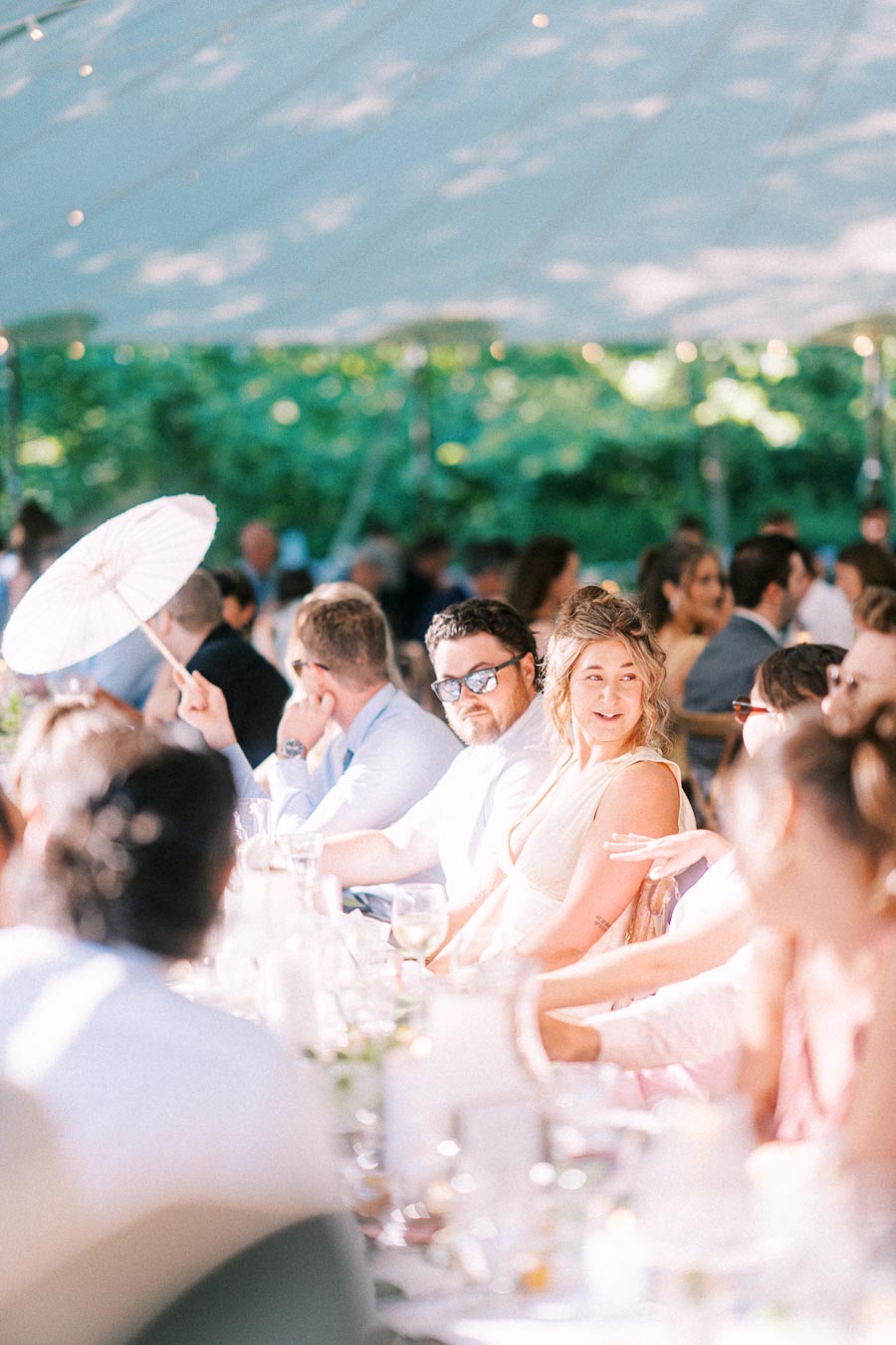 Wedding guests seated at a long outdoor dinner table under a white tent on a private farm estate near Chatham-Kent, Ontario, Canada.