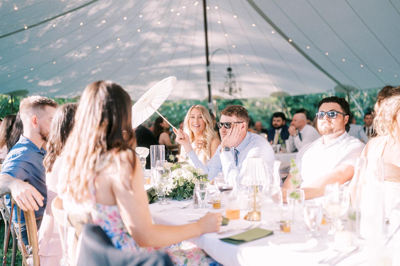 Wedding guests seated at a round dinner table under a white tent on a private farm estate near Chatham-Kent, Ontario, Canada.