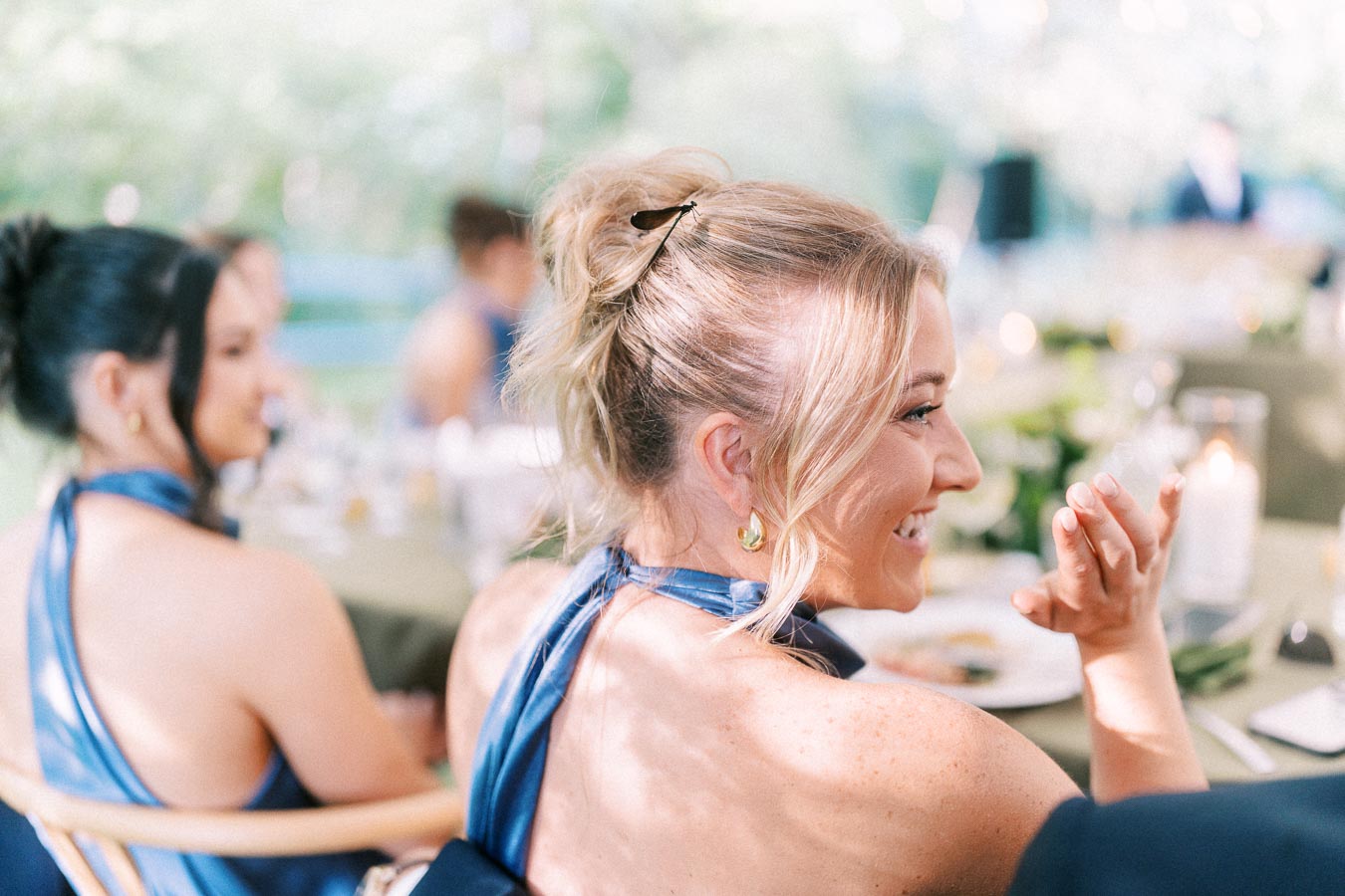 Smiling bridesmaid in a blue dress seated at an outdoor wedding dinner near Chatham-Kent, Ontario.