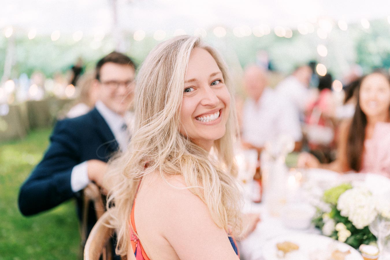 Smiling blonde woman at an outdoor tented wedding dinner on a private farm estate near Chatham-Kent, Ontario, Canada.