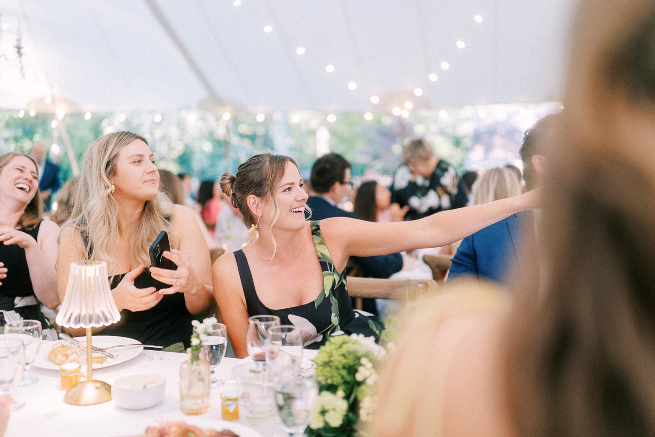 Wedding guests laughing and taking photos during a tented outdoor reception on a private estate near Chatham-Kent, Ontario, Canada.