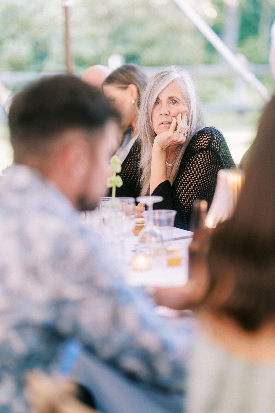 Woman seated among guests during a tented outdoor wedding dinner near Chatham-Kent, Ontario, Canada.