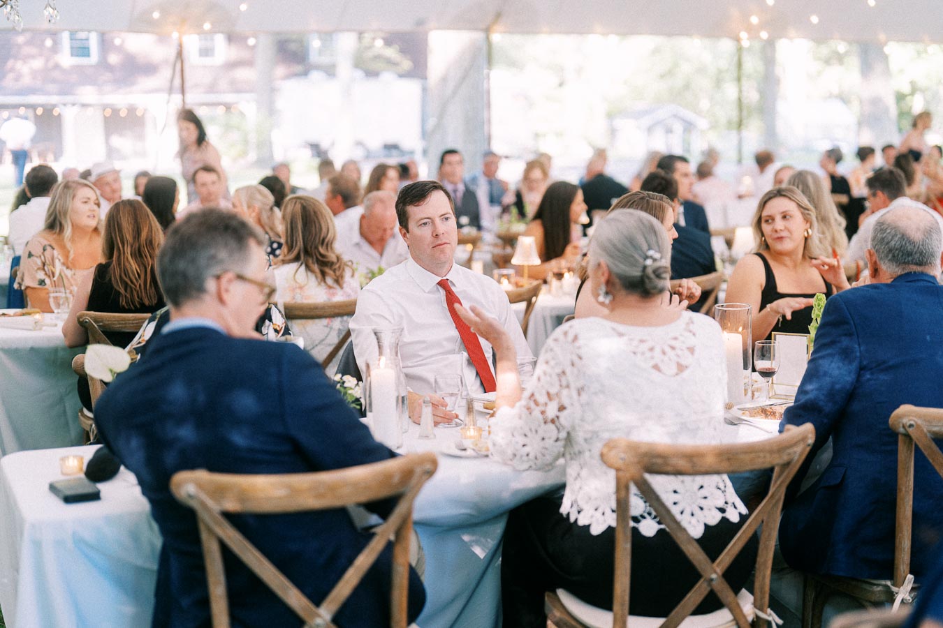 Wedding guests dining under a white reception tent on a private farm estate near Chatham-Kent, Ontario, Canada.