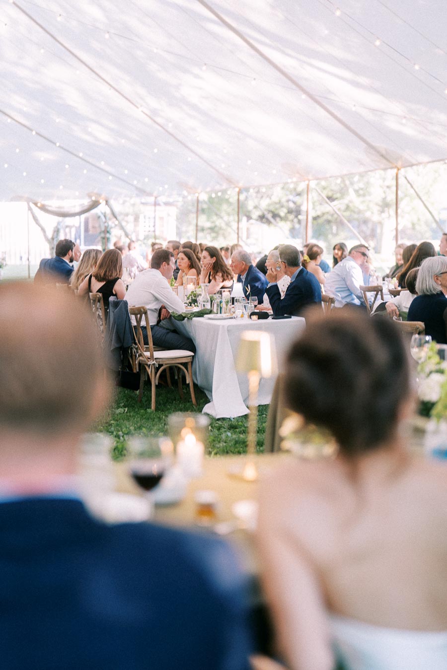 Wedding guests dining at round tables under a white tent during an outdoor private estate reception near Chatham-Kent, Ontario, Canada.