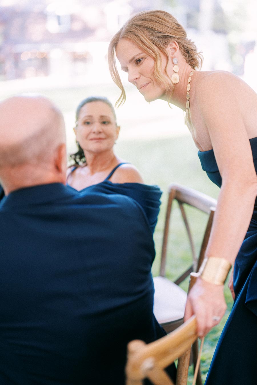 Wedding guests in formal navy attire talking during an outdoor tented reception near Chatham-Kent, Ontario.