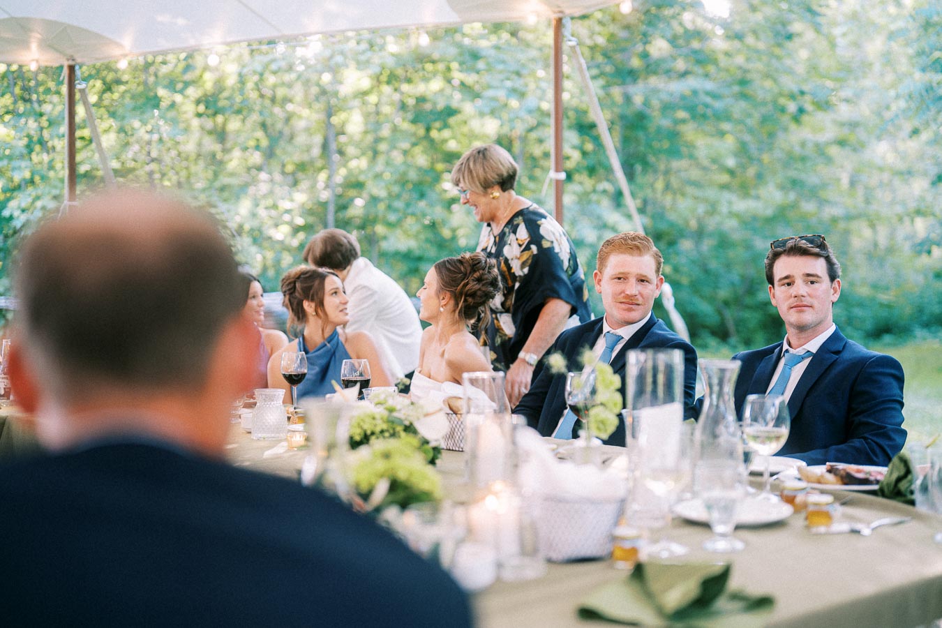 Wedding guests seated at a decorated dinner table under a tent during an outdoor farm wedding near Chatham-Kent, Ontario, Canada.