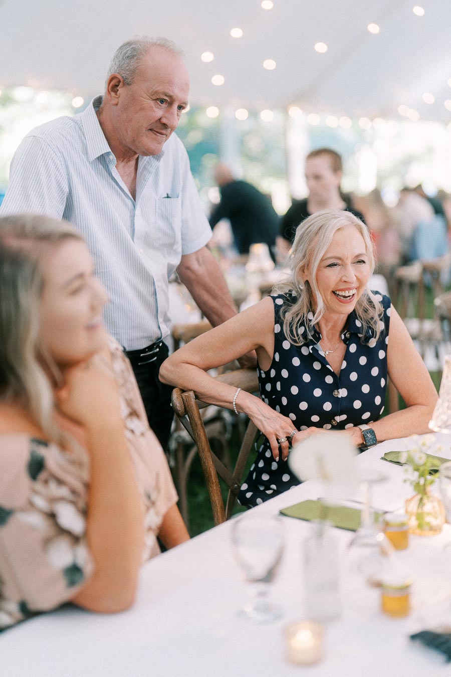 Wedding guests laughing during a tented outdoor reception at a private farm estate near Chatham-Kent, Ontario, Canada.