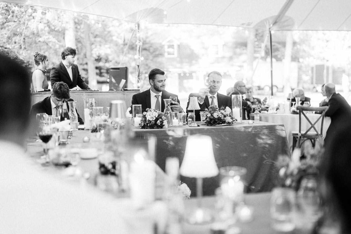 Black and white photo of a wedding reception dinner under a tent on a private estate near Chatham-Kent, Ontario, with guests seated at decorated tables.