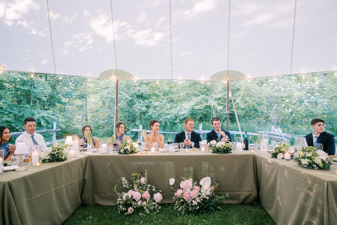 Bride, groom, and guests seated at a decorated outdoor wedding dinner table under a tent near Chatham-Kent, Ontario.