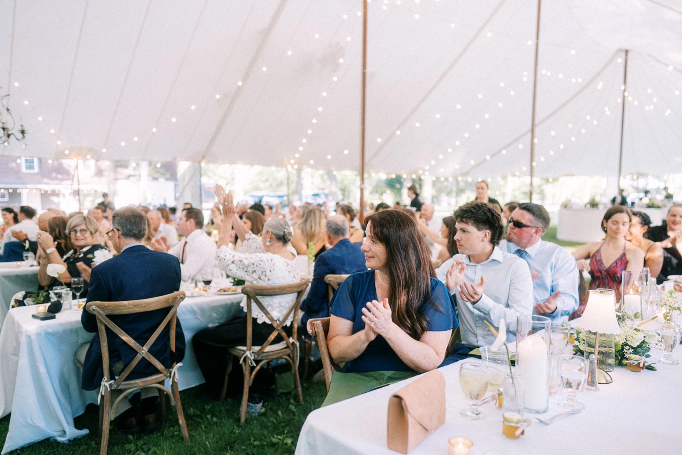 Wedding guests applauding during a tented outdoor reception on a private farm estate near Chatham-Kent, Ontario, Canada.