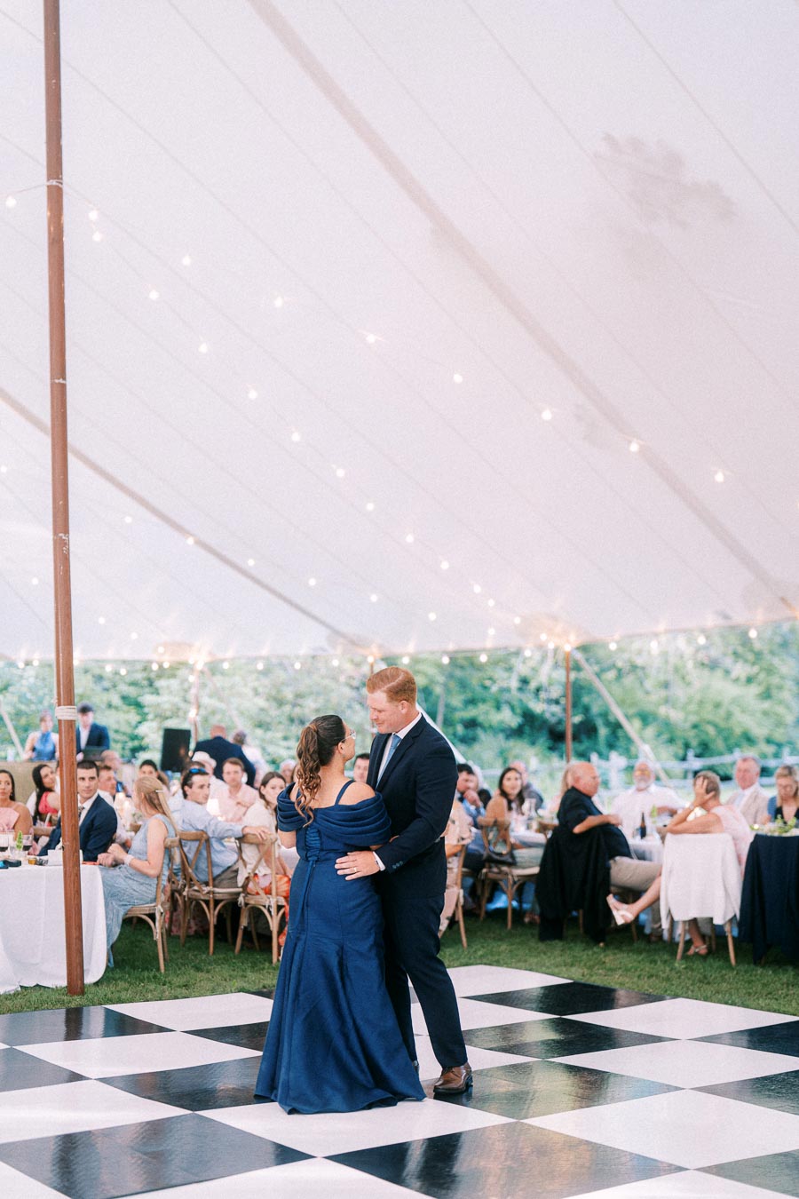 Couple dancing on a black and white checkered floor inside a white tented wedding reception near Chatham-Kent, Ontario.