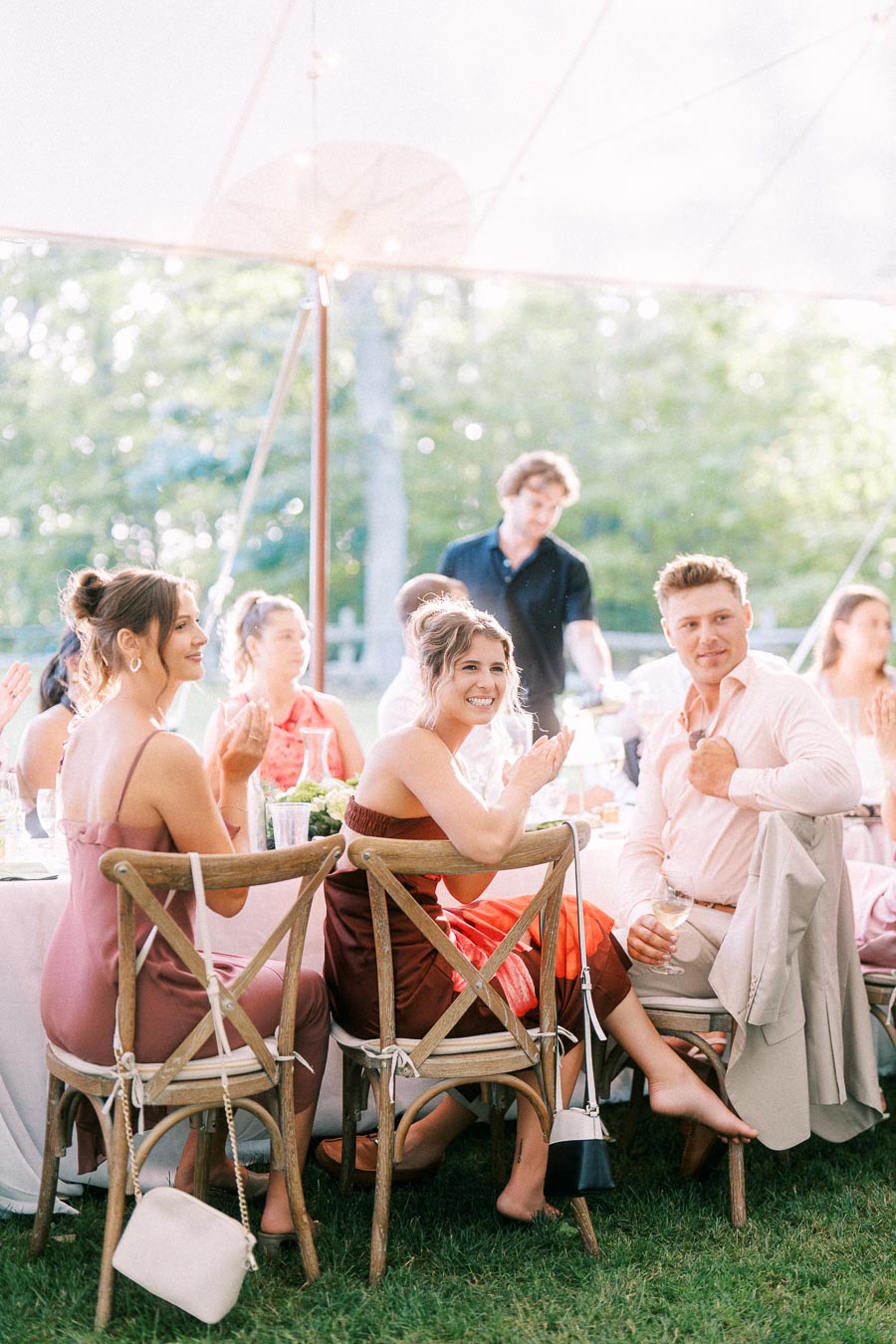 Wedding guests seated at round tables under a white tent during an outdoor farm reception near Chatham-Kent, Ontario, Canada.