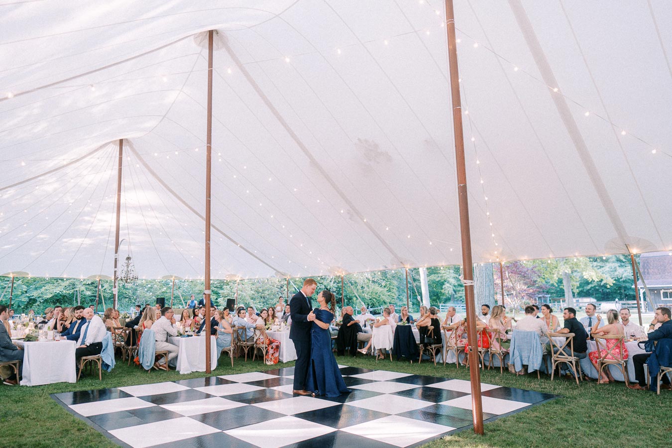Bride and groom dancing on a black and white floor during a tented outdoor wedding reception near Chatham-Kent, Ontario.