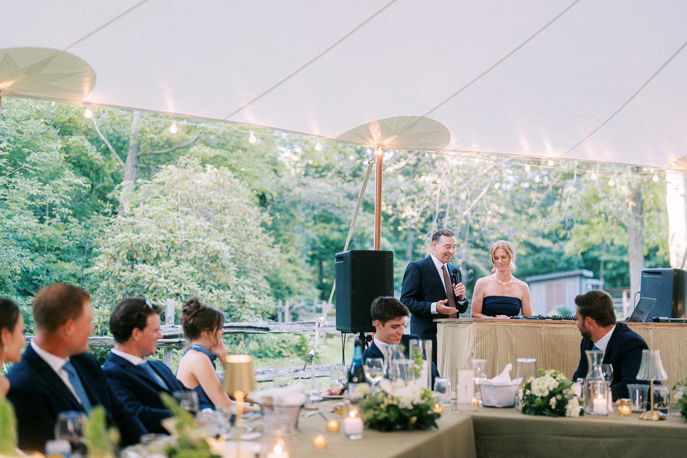 Outdoor tented wedding reception on a private farm estate near Chatham-Kent, Ontario, with guests seated at dinner tables during speeches.