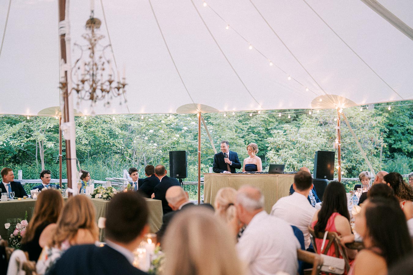 Wedding reception dinner under a white tent on a private estate near Chatham-Kent, Ontario, with guests seated and speakers at the head table.