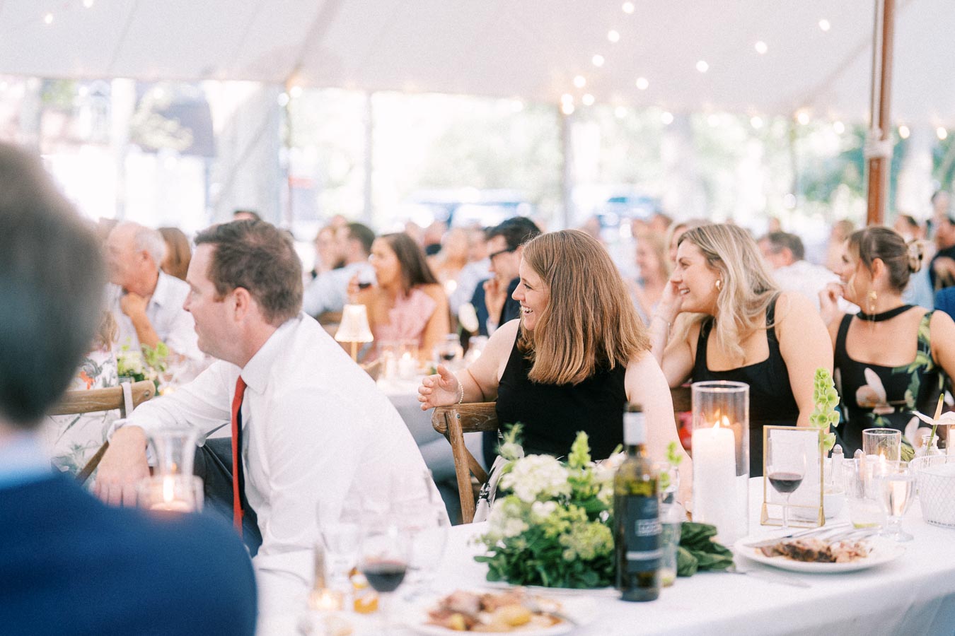 Wedding guests seated at a dinner table inside a white reception tent on a private farm estate near Chatham-Kent, Ontario.