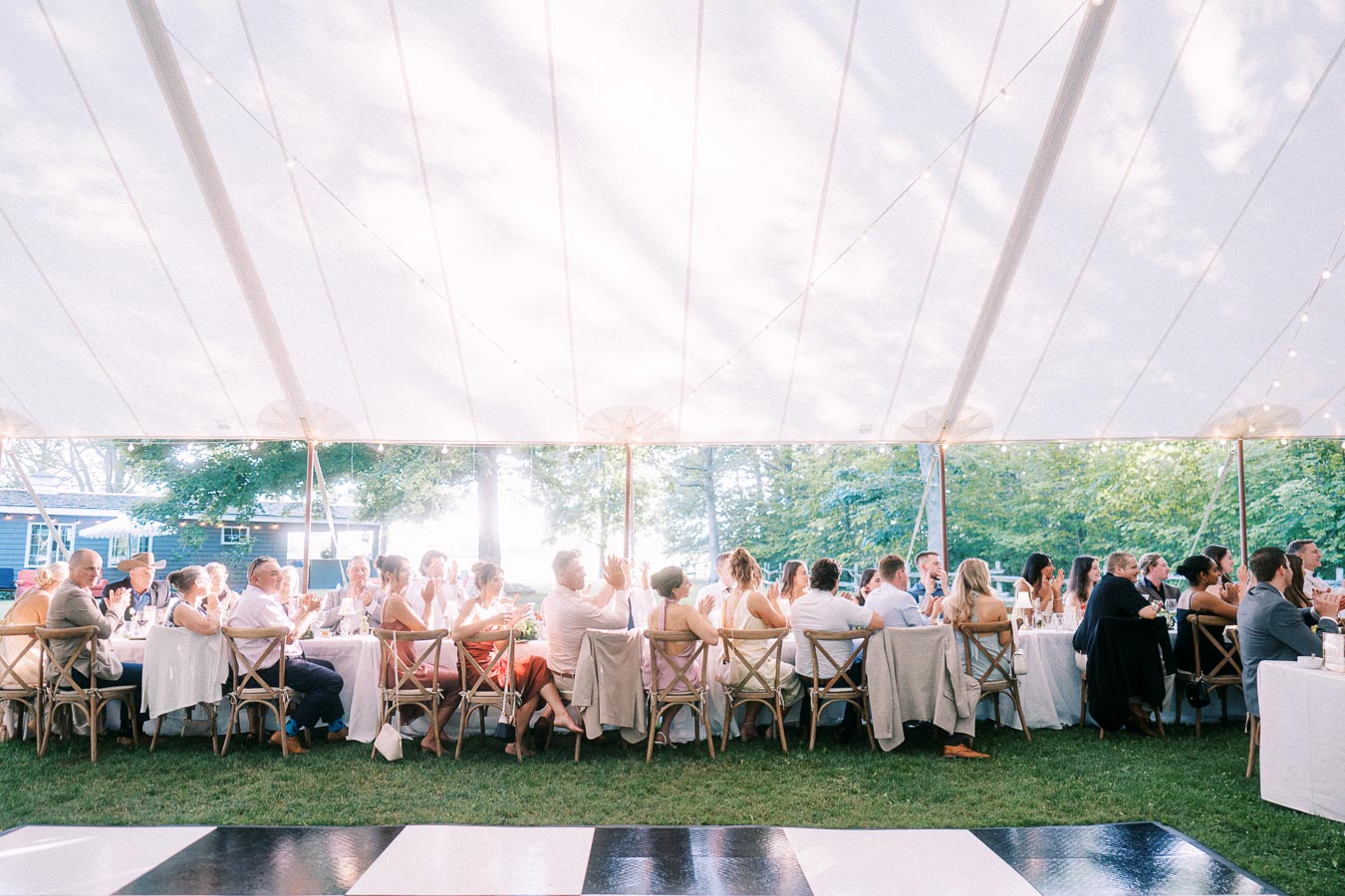 Outdoor tented wedding reception dinner on a private farm estate near Chatham-Kent, Ontario, with guests seated at long tables beside a dance floor.