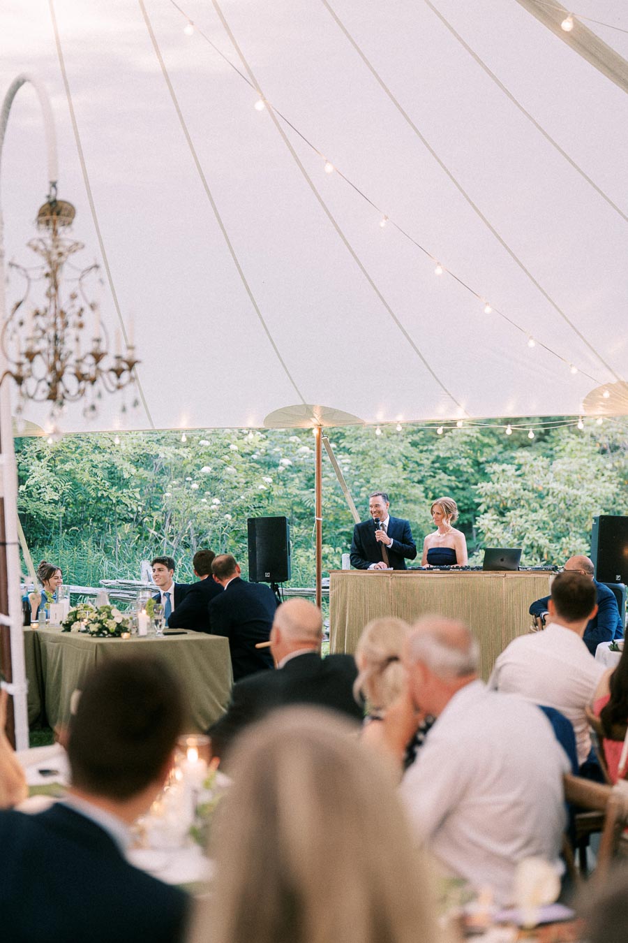 Outdoor tented wedding reception on a private estate near Chatham-Kent, Ontario, with guests seated for dinner as a speaker addresses the crowd.