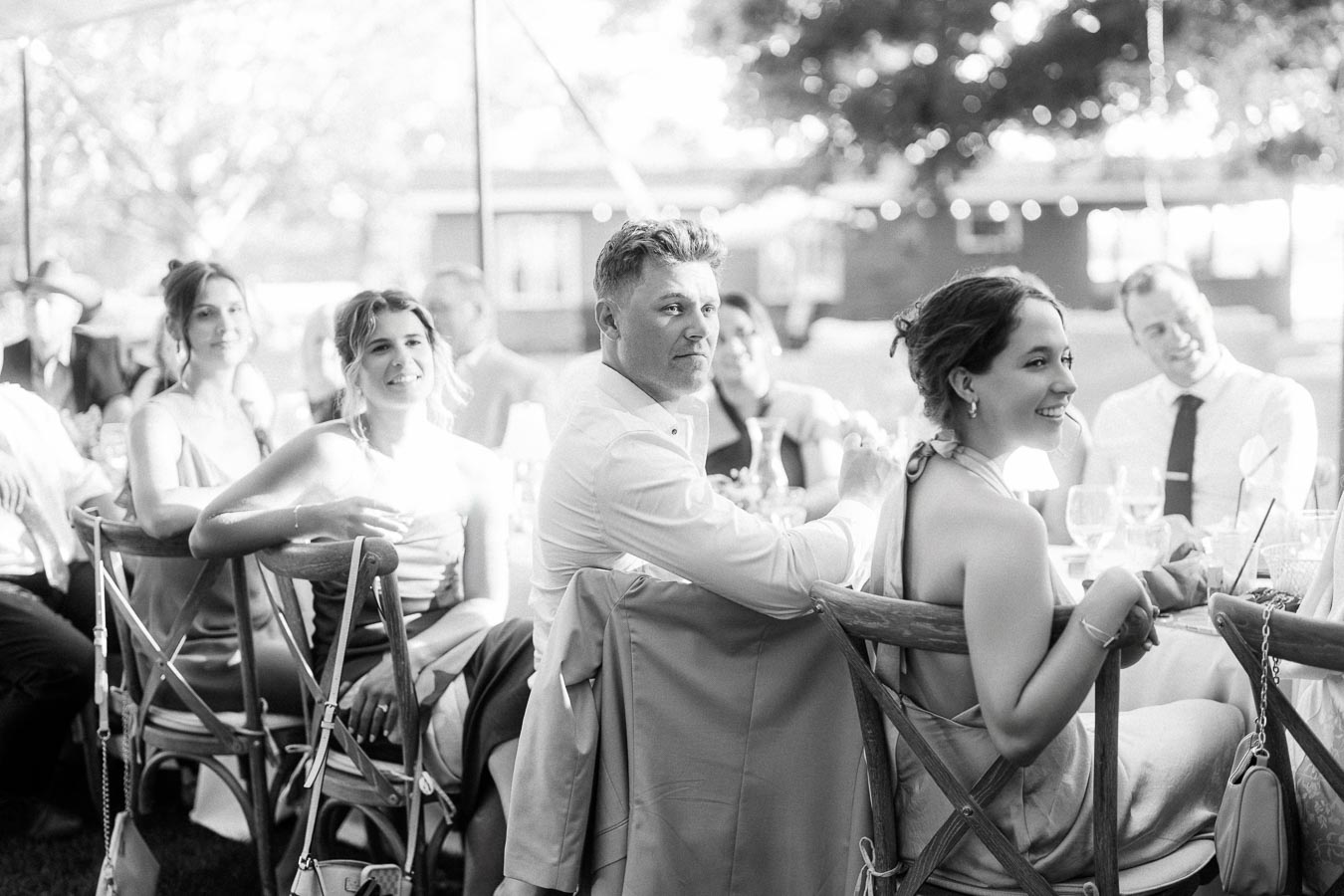 Black and white photo of wedding guests seated at outdoor reception tables under a tent on a private farm estate near Chatham-Kent, Ontario, Canada.