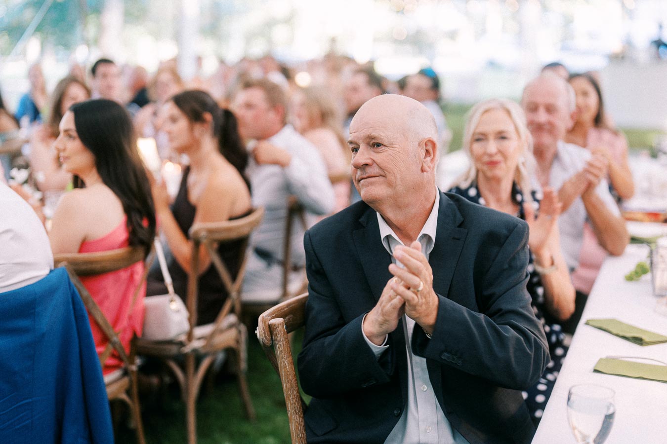 Wedding guests applauding during a tented outdoor reception on a private farm estate near Chatham-Kent, Ontario, Canada.