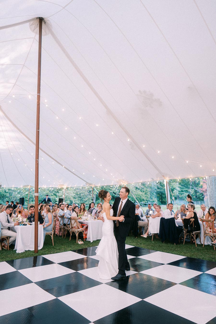 Bride and groom dancing on a black and white checkered floor inside a tented outdoor wedding reception near Chatham-Kent, Ontario.