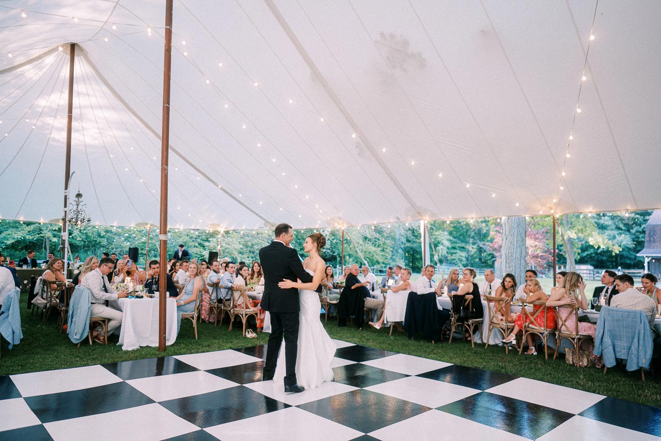 Bride and groom dance on a checkered floor under a white wedding tent during an outdoor farm reception near Chatham-Kent, Ontario.