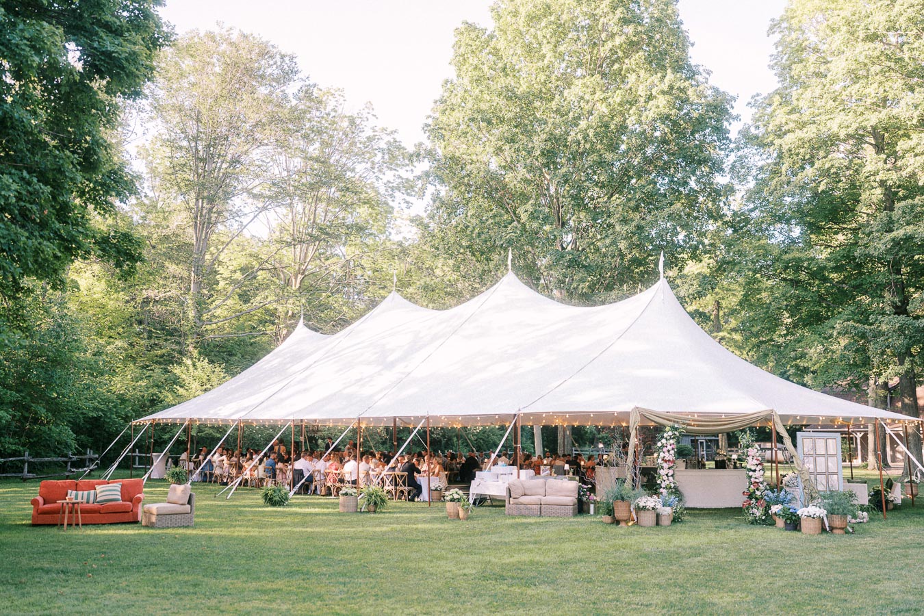 White wedding reception tent on a grassy private estate near Chatham-Kent, Ontario, with seated guests, lounge furniture, flowers, and trees.