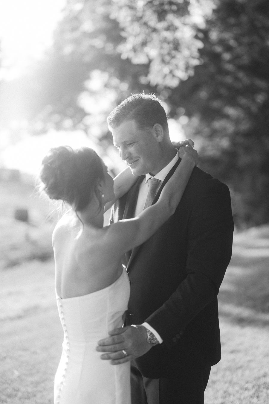 Black and white portrait of a bride and groom embracing outdoors on a private farm estate near Chatham-Kent, Ontario.