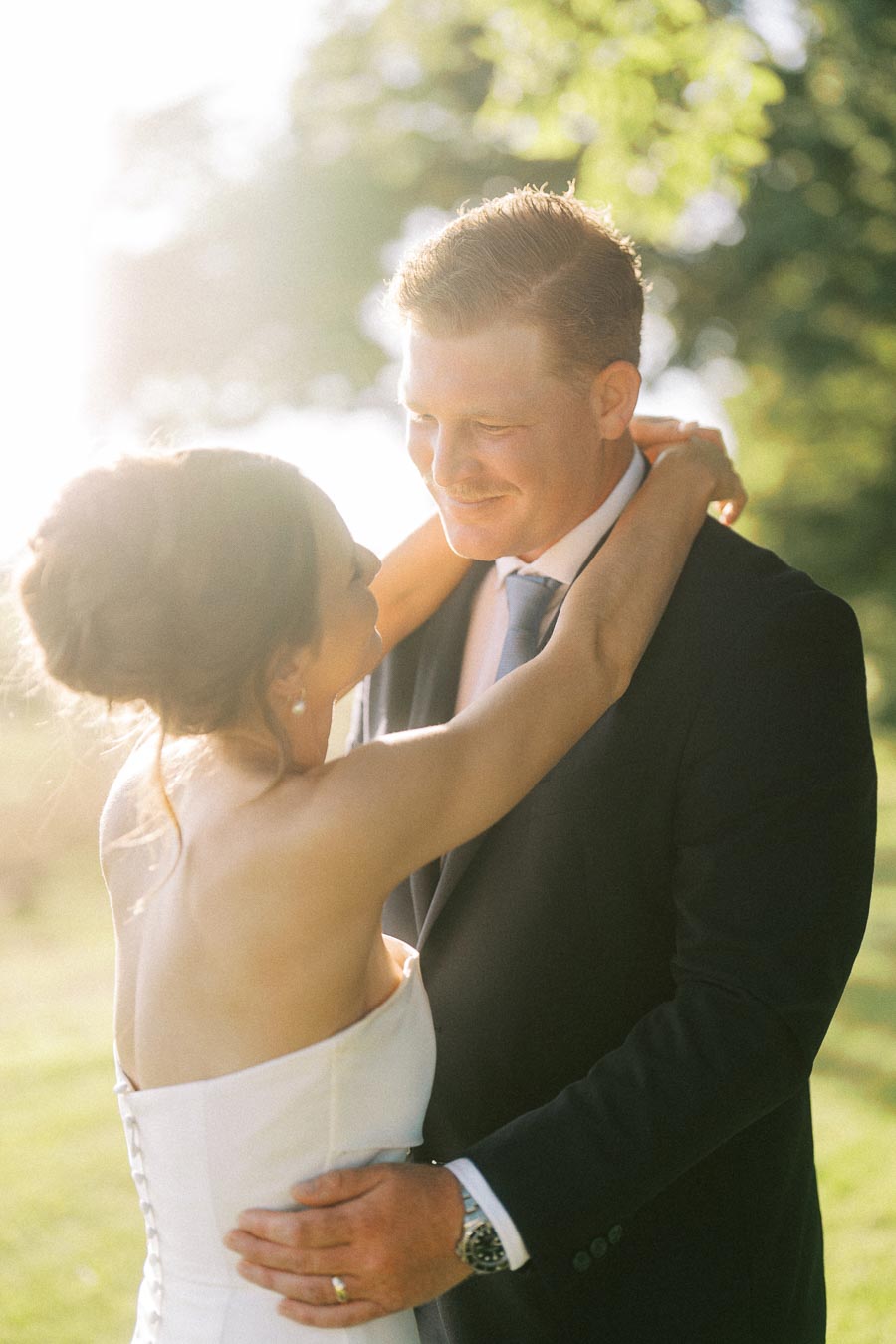 Bride and groom embrace outdoors in golden sunlight during a private estate wedding near Chatham-Kent, Ontario, Canada.