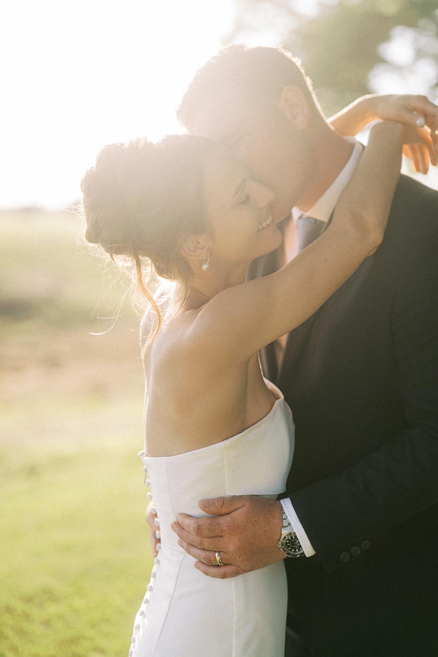 Bride and groom embrace outdoors at a farm wedding near Chatham-Kent, Ontario, Canada, with warm golden sunlight and soft romantic backlight.