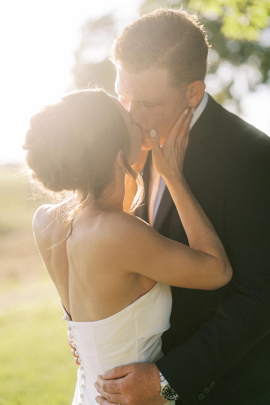 Bride and groom kissing outdoors in warm sunlight during a private estate wedding near Chatham-Kent, Ontario, Canada.