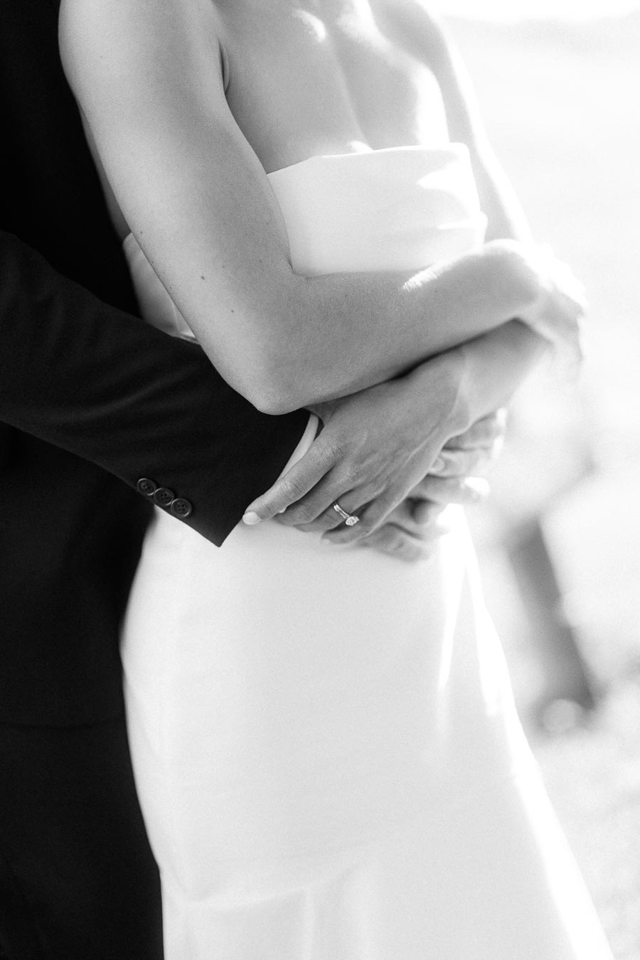 Black and white close up of a bride and groom embracing, with the bride wearing a strapless gown and engagement ring near Chatham-Kent, Ontario.