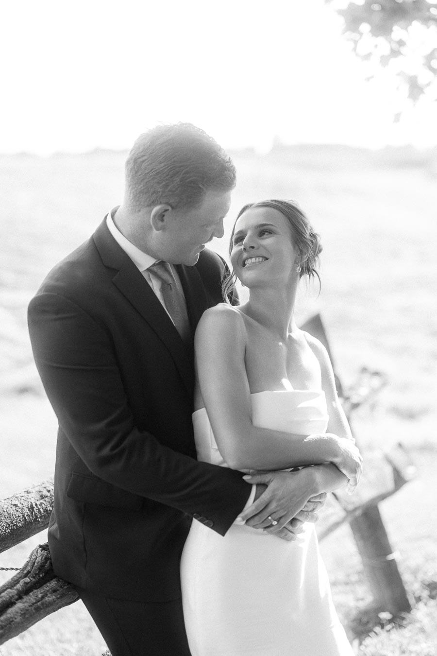 Black and white portrait of a bride and groom embracing outdoors on a private farm estate near Chatham-Kent, Ontario.