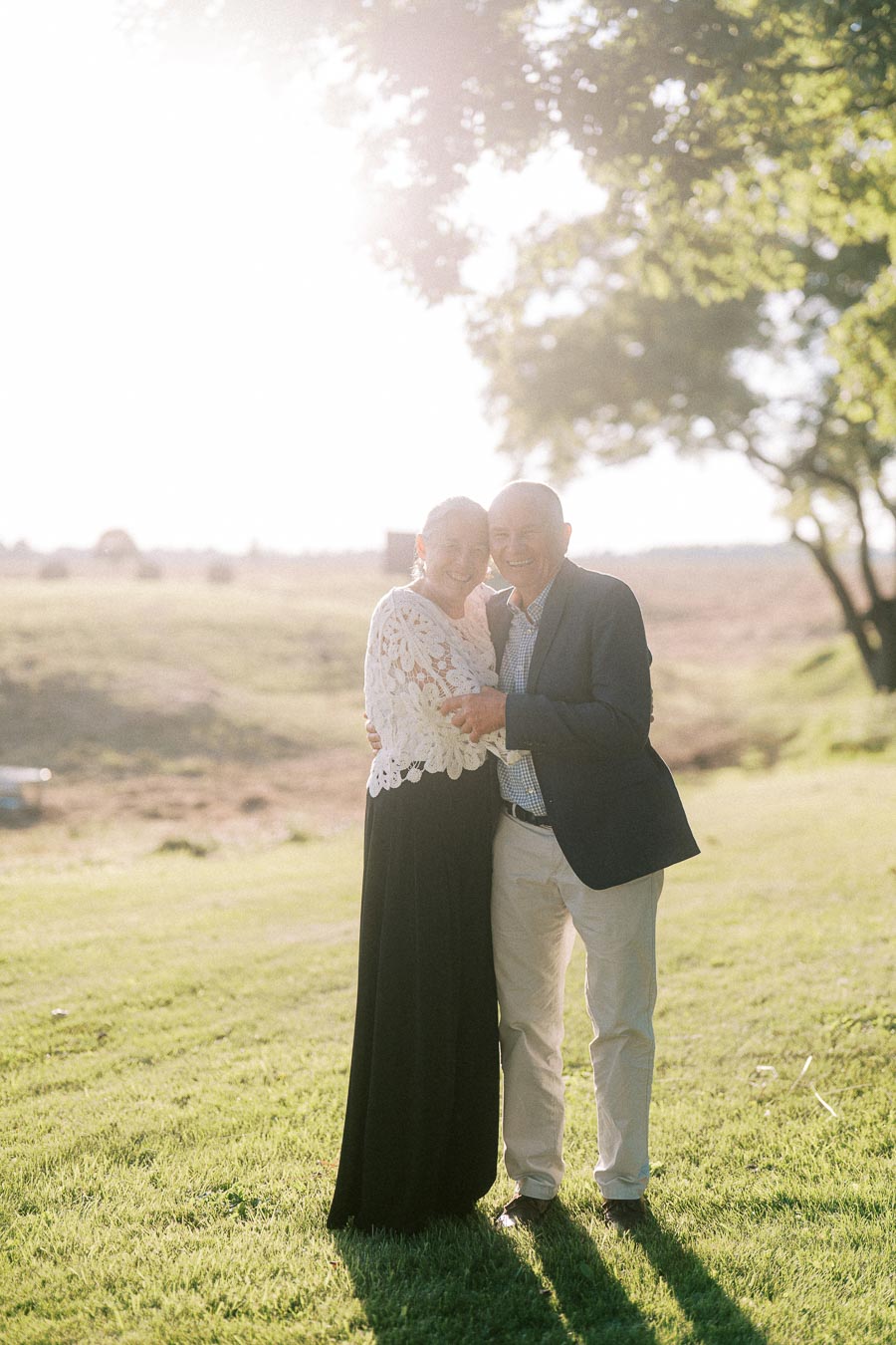 Smiling older couple embracing on a grassy farm field during an outdoor private estate wedding near Chatham-Kent, Ontario, Canada.