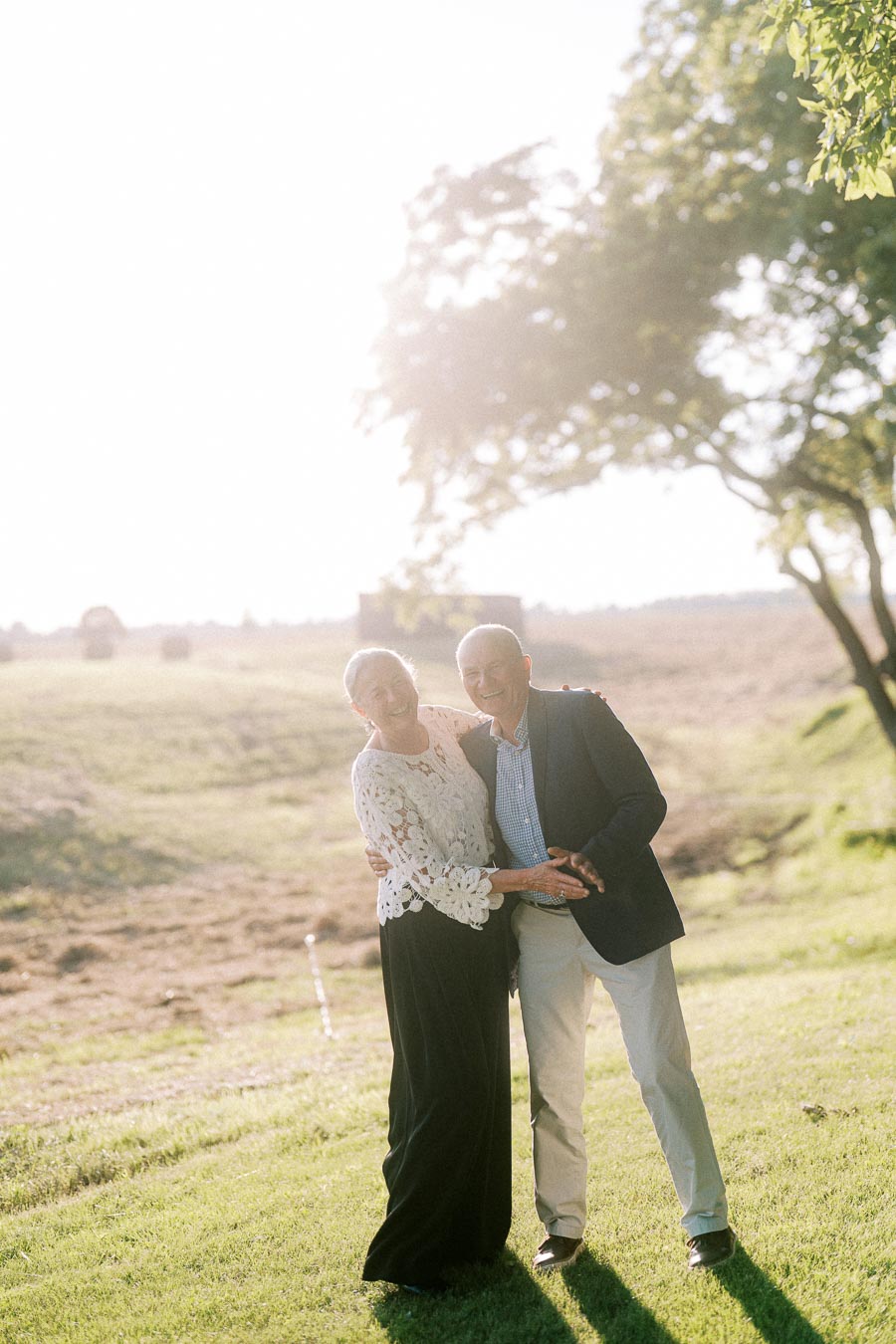 Smiling older couple standing together on a grassy farm field at an outdoor private estate wedding near Chatham-Kent, Ontario, Canada.